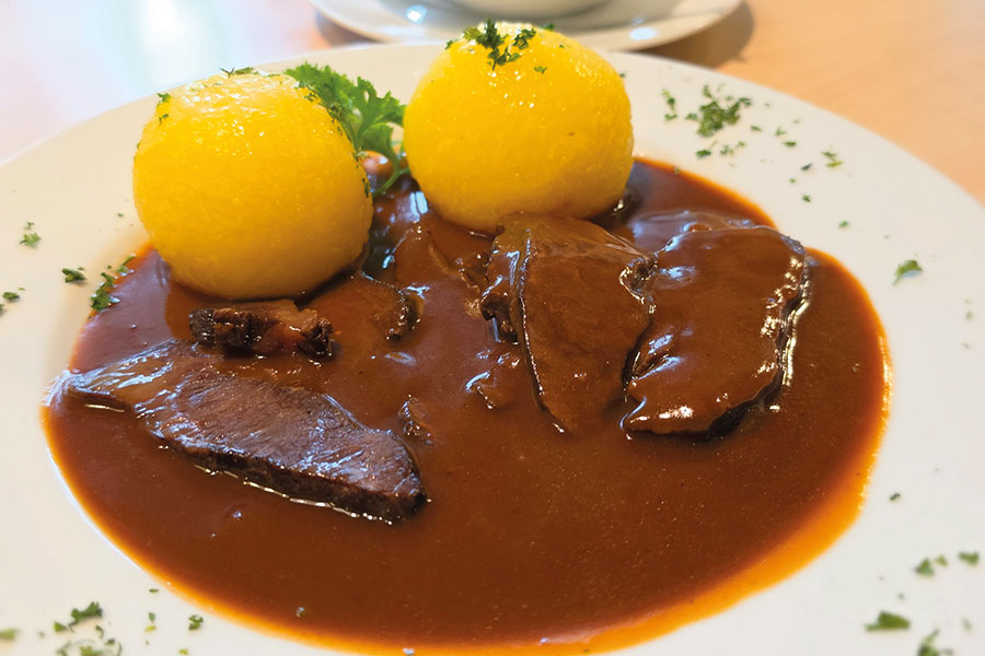 Braten mit Kartoffelklößen und Soße auf einem Teller